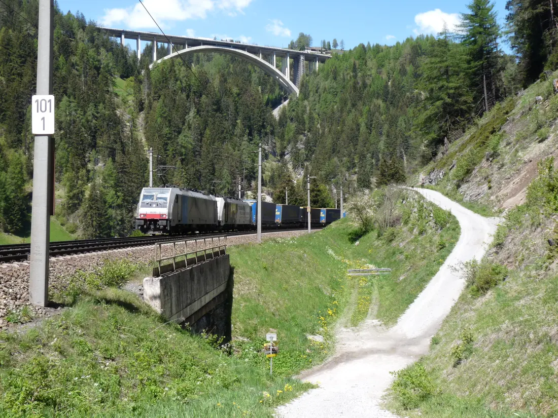 Zug auf der Brennerbahn im Wipptal, darüber die Bögen der Europabrücke.